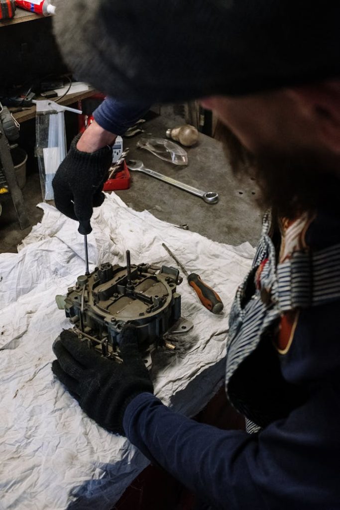 Mechanic at work fixing engine component in garage environment.